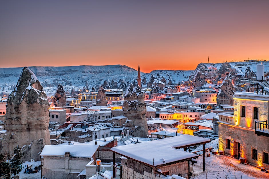 Stunning winter sunset view of Göreme in Cappadocia, Türkiye, highlighting the unique fairy chimneys and snowy landscape.