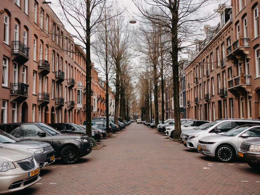 A picturesque Amsterdam street lined with brick buildings and parked cars, capturing urban charm.