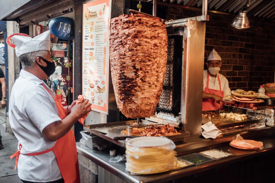 Street view of taco vendors serving traditional tacos al pastor in Mexico City.