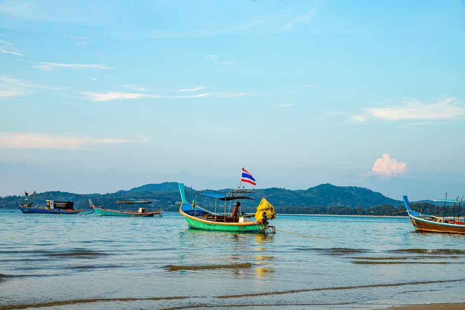 Traditional long-tail boats anchored on a tranquil sea in Phuket, Thailand during day time.