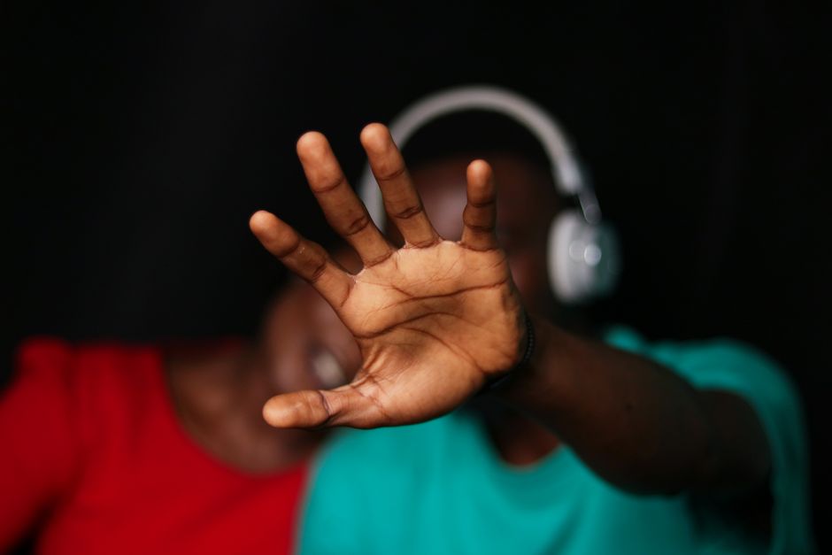 Close-up of a young couple with a hand gesture and headphones, expressing emotion indoors.