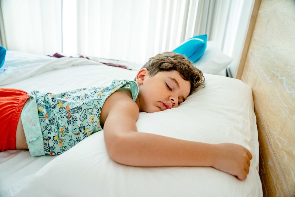 Young caucasian boy sleeping peacefully on a white pillow indoors.