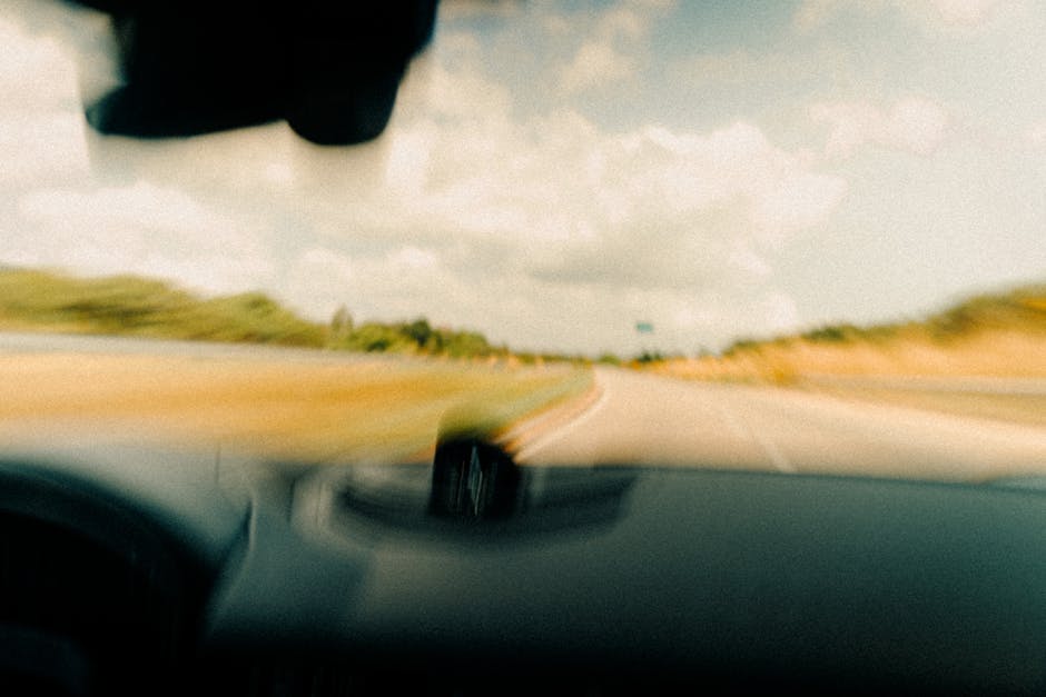 Dynamic blurred image from a vehicle's windshield capturing a rural road in motion.