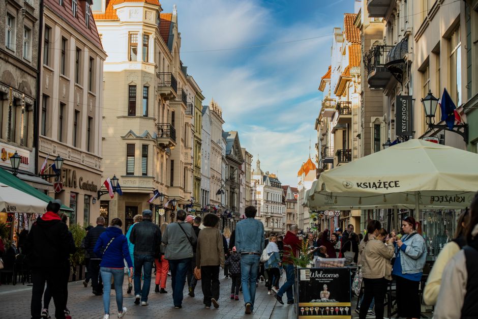Lively urban scene on a European street with historic buildings and bustling crowd.