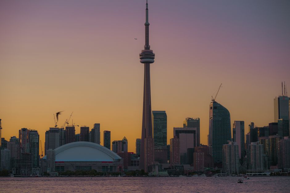 Beautiful Toronto skyline at sunset with the iconic CN Tower and reflections in the water.