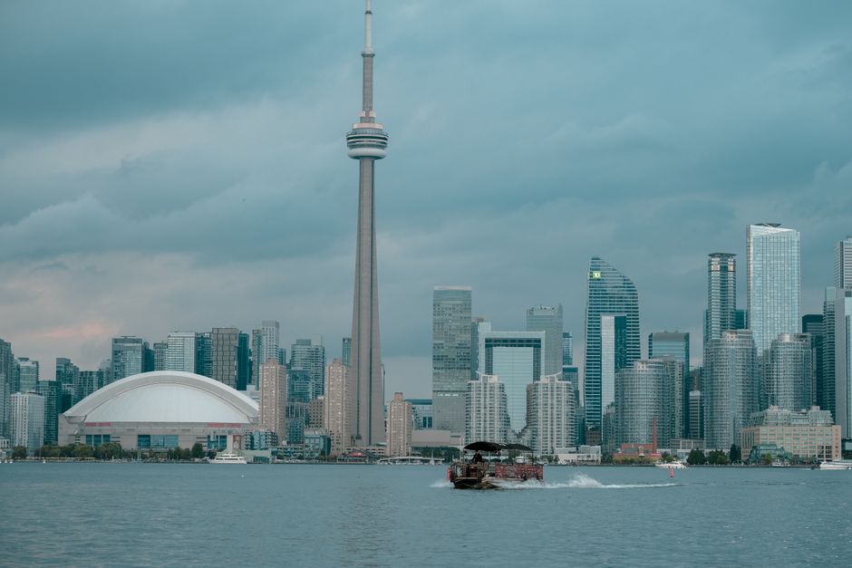 Toronto skyline with CN Tower and waterfront view under cloudy skies.