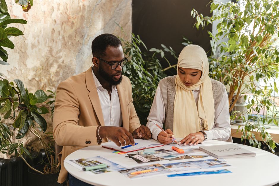 African American man and Arabic woman working together on a project at a table.