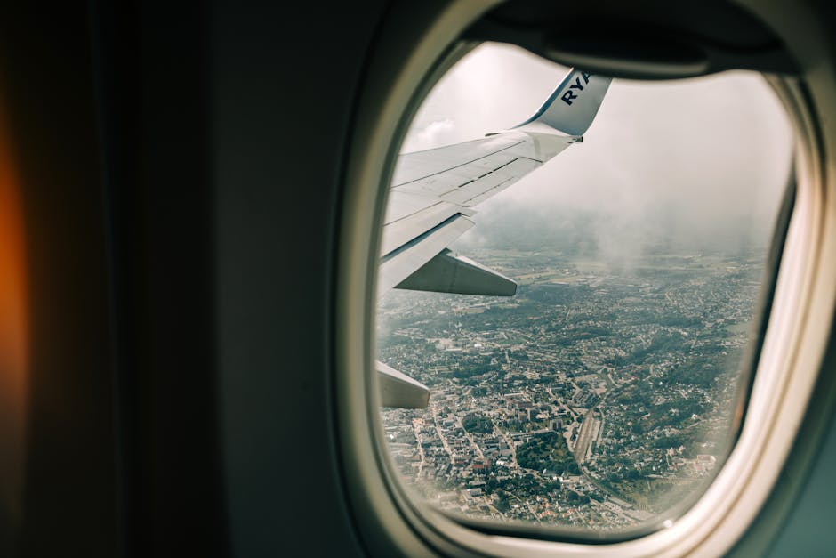 Scenic view of city from airplane window with wing visible, perfect for travel themes.