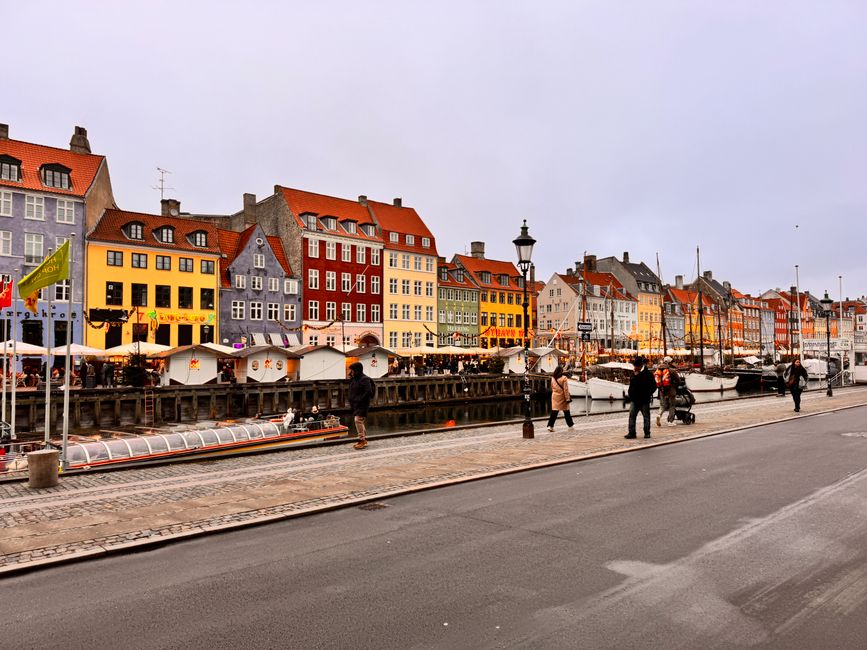View of the vibrant Nyhavn waterfront in Copenhagen, Denmark, showcasing historic colorful buildings and busy street scene.