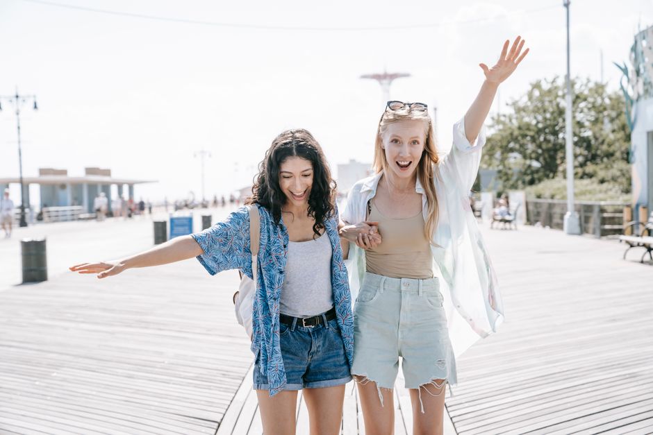 Two women having fun on a sunny boardwalk, embracing friendship and summer vibes.