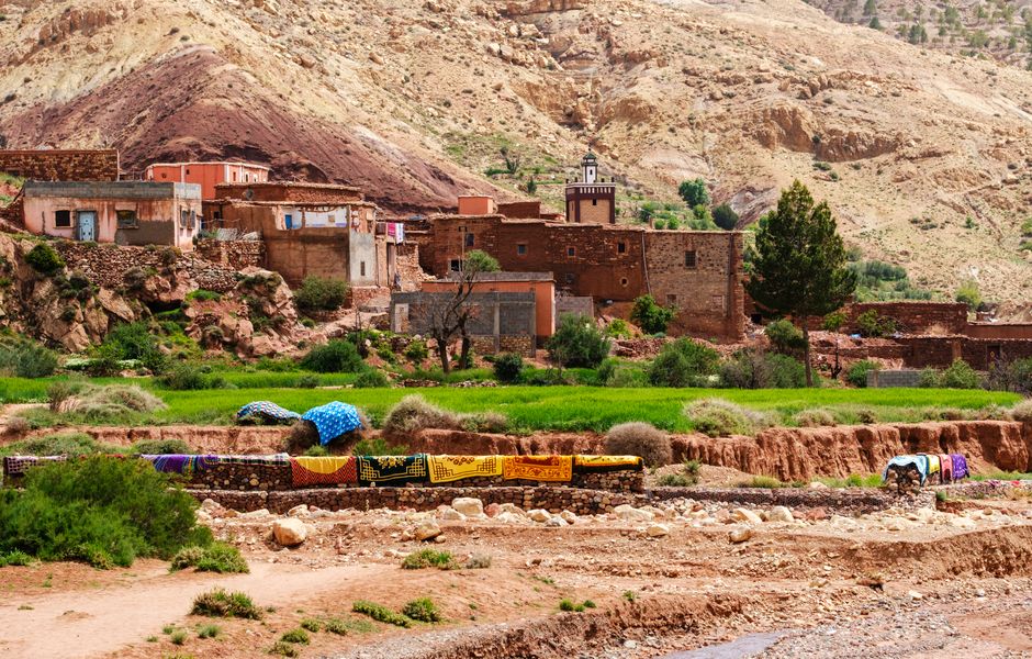 Scenic view of a Berber village in the Atlas Mountains, Morocco, with colorful textiles.