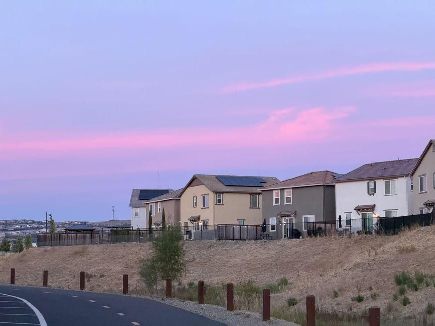 Charming suburban neighborhood with a vibrant pink sky at sunset, highlighting modern homes.