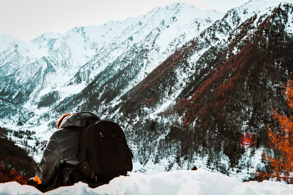 A person with a backpack admires the snowy mountains of Prali, Piemonte, Italy.