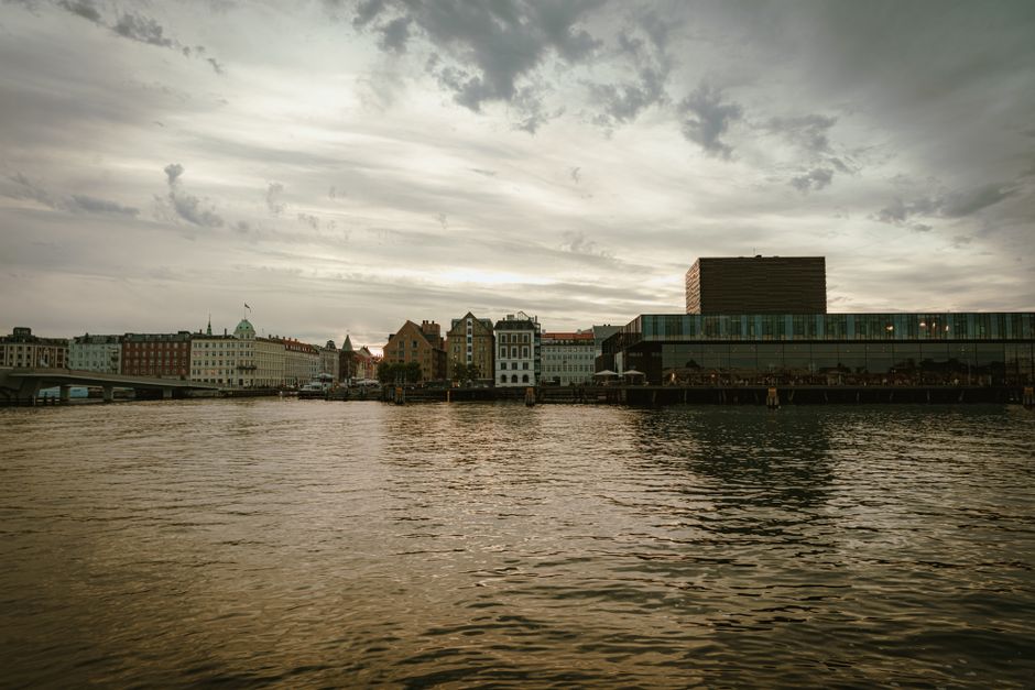 Beautiful waterfront cityscape at dusk with historic buildings and modern architecture reflecting on the water.