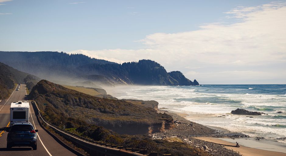 A breathtaking view of Oregon's coastal road and rugged beaches under a clear sky, ideal for travel enthusiasts.