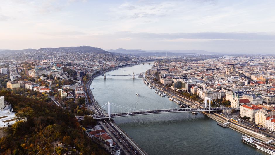 Stunning aerial view of Budapest featuring the Danube River and iconic city bridges during the day.