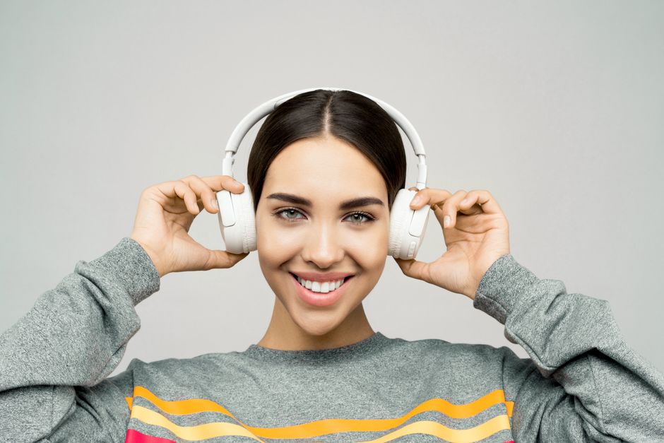 Portrait of a woman smiling while enjoying music with wireless headphones.