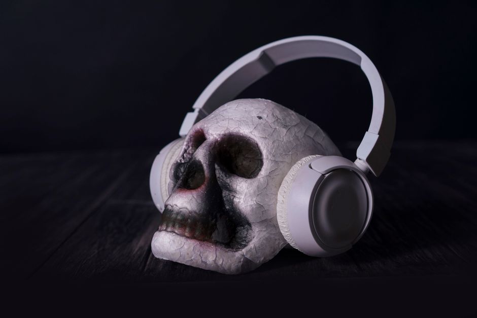A close-up of a skull wearing headphones in a dark, moody setting, ideal for dramatic themes.