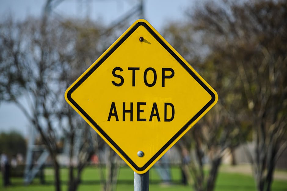 Vibrant yellow stop ahead sign in an outdoor park setting in Dallas, Texas.
