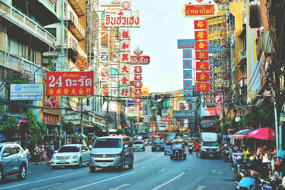 Vibrant cityscape of Bangkok's Chinatown with busy streets and colorful signs.