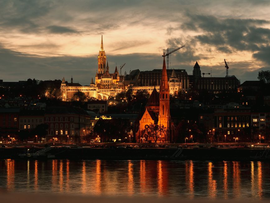 Captivating view of Buda Castle and Matthias Church at sunset over the Danube River.
