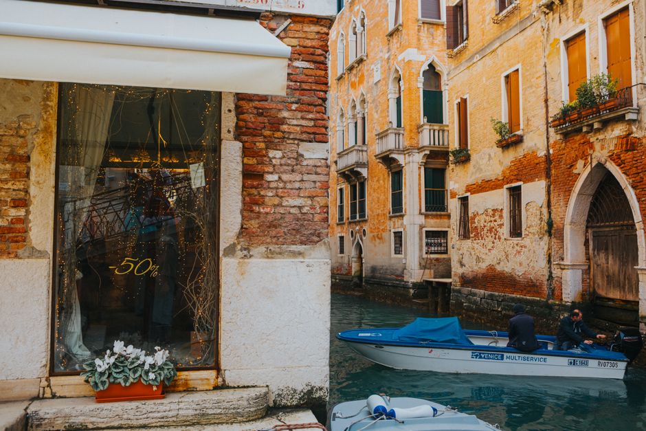 Quaint Venetian canal scene with charming brick buildings and a blue boat on the water.