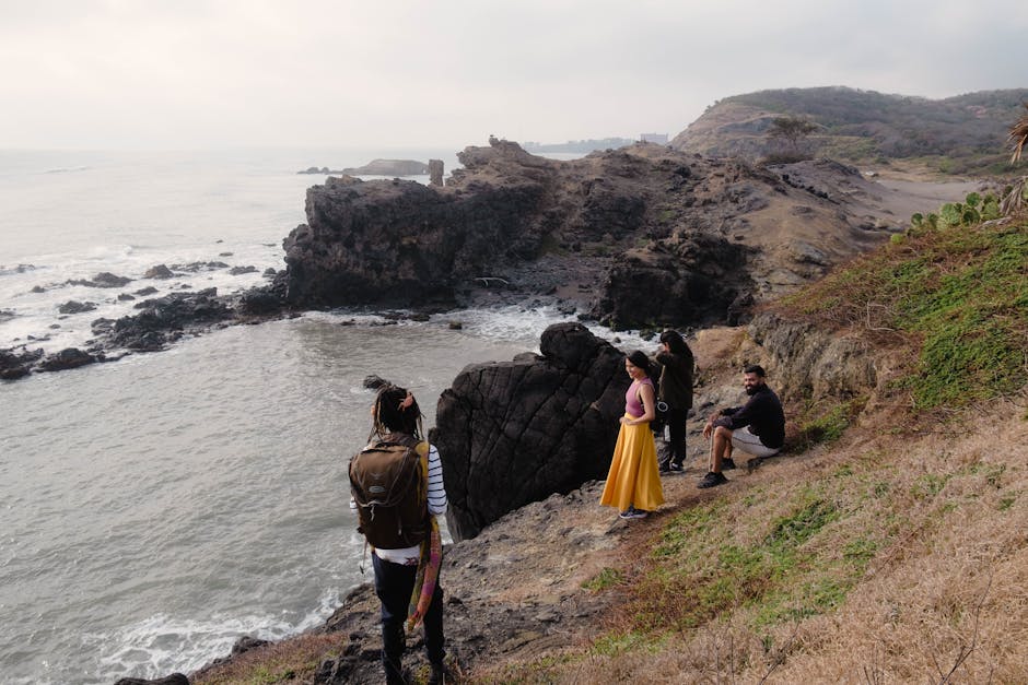 A group of friends enjoying scenic views on a rugged rocky coastline during daytime.