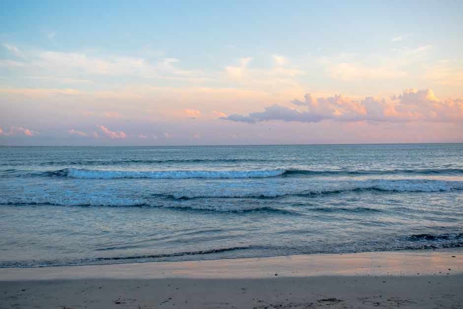 Serene ocean waves at sunrise in Kamakura, Japan, with calm seas and pastel skies.