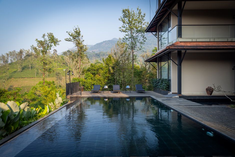 Modern villa with infinity pool, lush greenery, and mountain backdrop, perfect for relaxation.