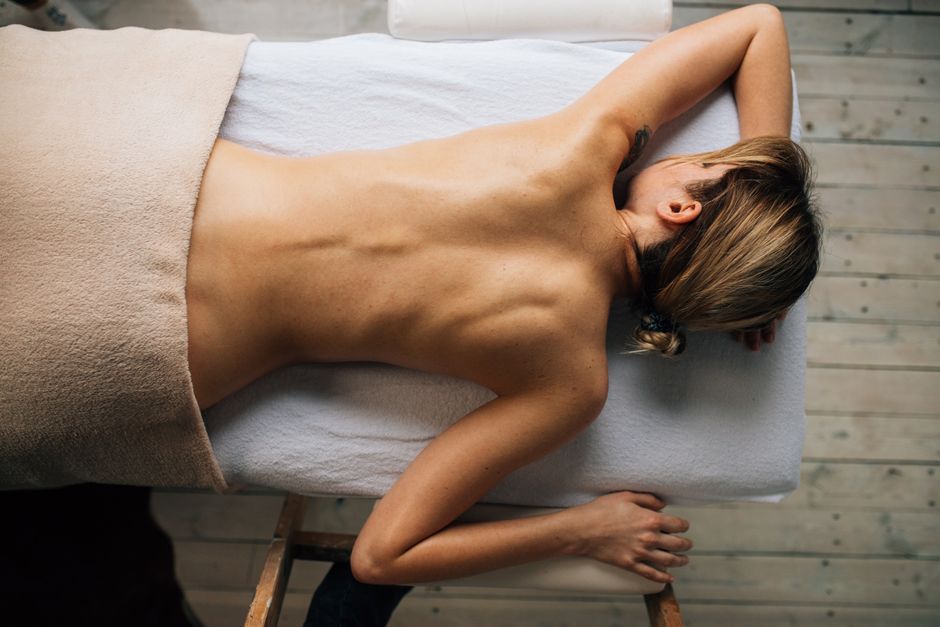 Relaxing massage therapy session with a woman lying topless on massage table.