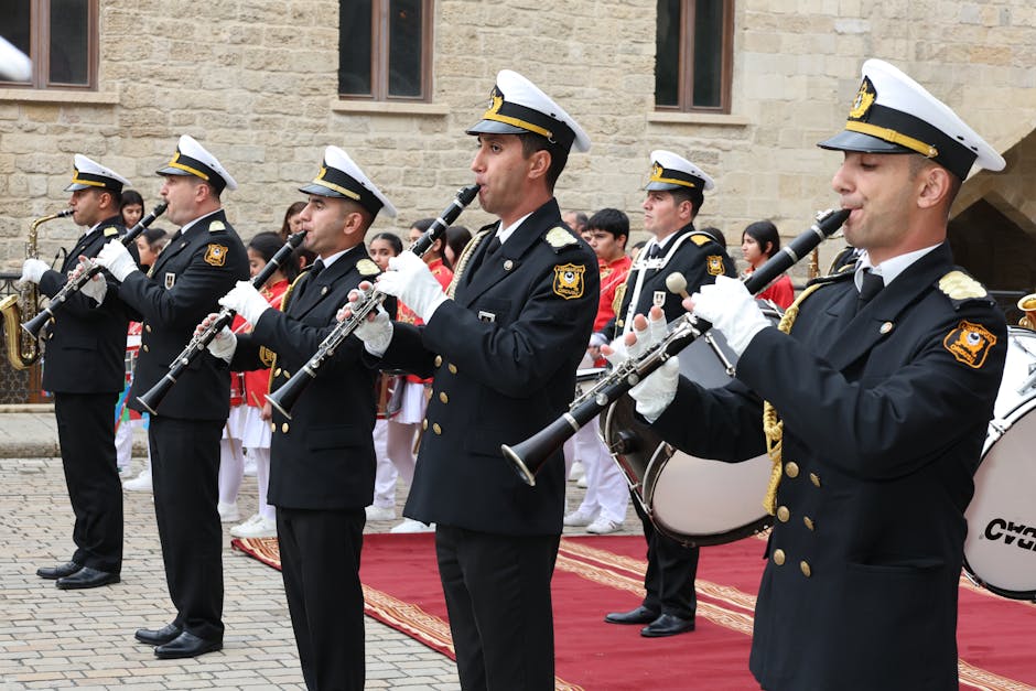 A military band in uniform performing with clarinets and saxophones during an outdoor ceremony.
